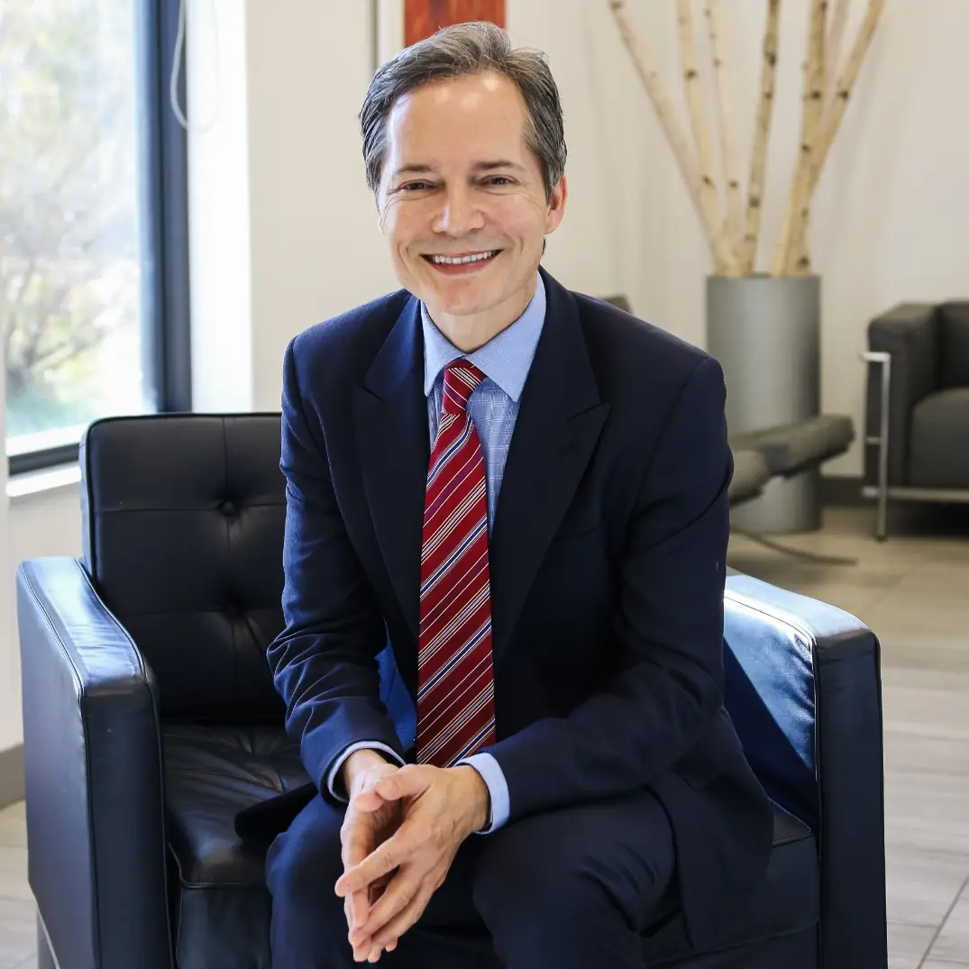 Ivan Wayne, MD, in a suit and tie, sits confidently in a chair.